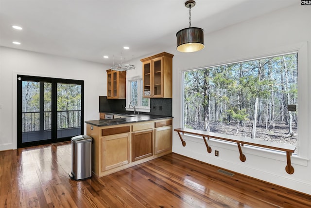 kitchen with dark wood-type flooring, dark countertops, visible vents, and decorative backsplash