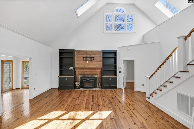 unfurnished living room featuring light wood-type flooring, a skylight, visible vents, and stairs