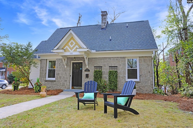 exterior space featuring stone siding, a chimney, a lawn, and roof with shingles