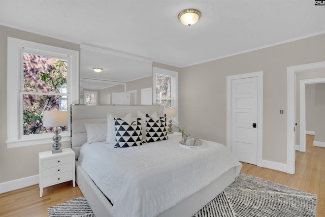 bedroom with ornamental molding, light wood-type flooring, and baseboards