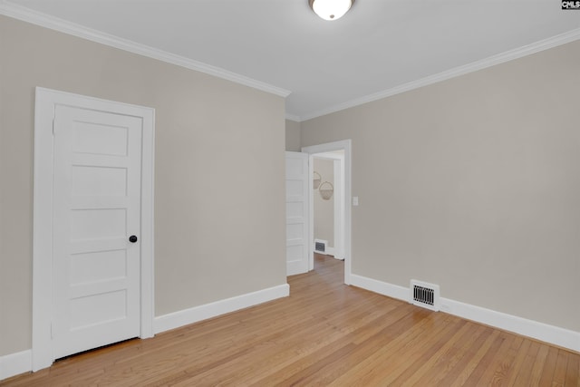 spare room featuring ornamental molding, light wood finished floors, visible vents, and baseboards