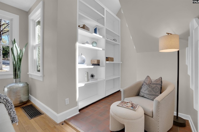 living area with wood finished floors, visible vents, and baseboards