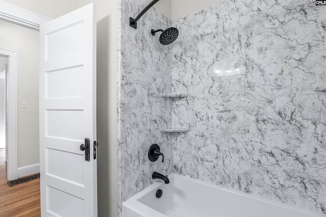 full bath featuring tub / shower combination, visible vents, baseboards, and wood finished floors