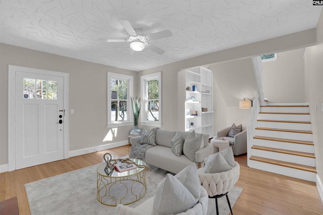 living room with light wood-style floors, baseboards, stairway, and a textured ceiling