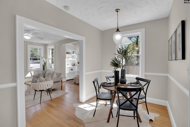 dining space featuring a textured ceiling, light wood-type flooring, and baseboards