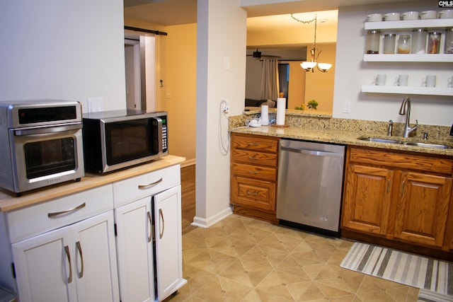 kitchen with a toaster, a barn door, appliances with stainless steel finishes, light stone counters, and a sink