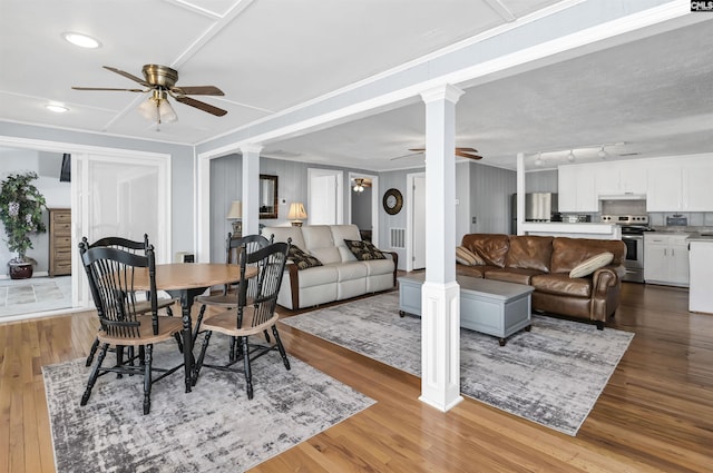 dining room with a ceiling fan, ornate columns, and wood finished floors