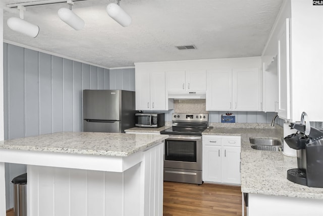 kitchen featuring visible vents, appliances with stainless steel finishes, white cabinetry, a sink, and under cabinet range hood