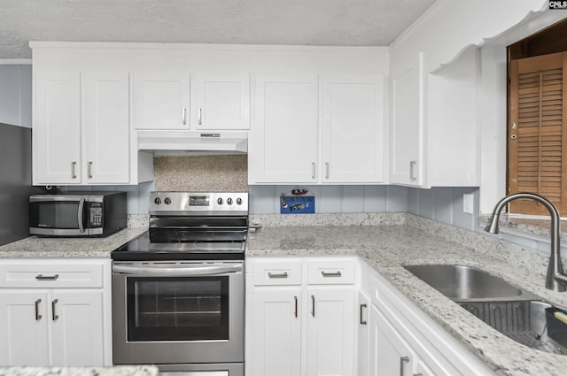 kitchen featuring decorative backsplash, white cabinets, appliances with stainless steel finishes, under cabinet range hood, and a sink