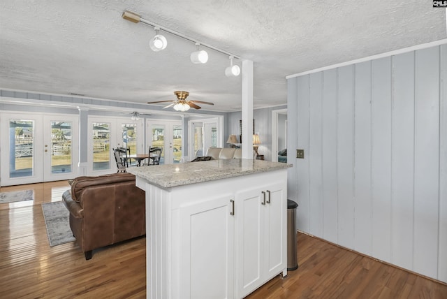 kitchen featuring white cabinets, open floor plan, wood finished floors, and french doors