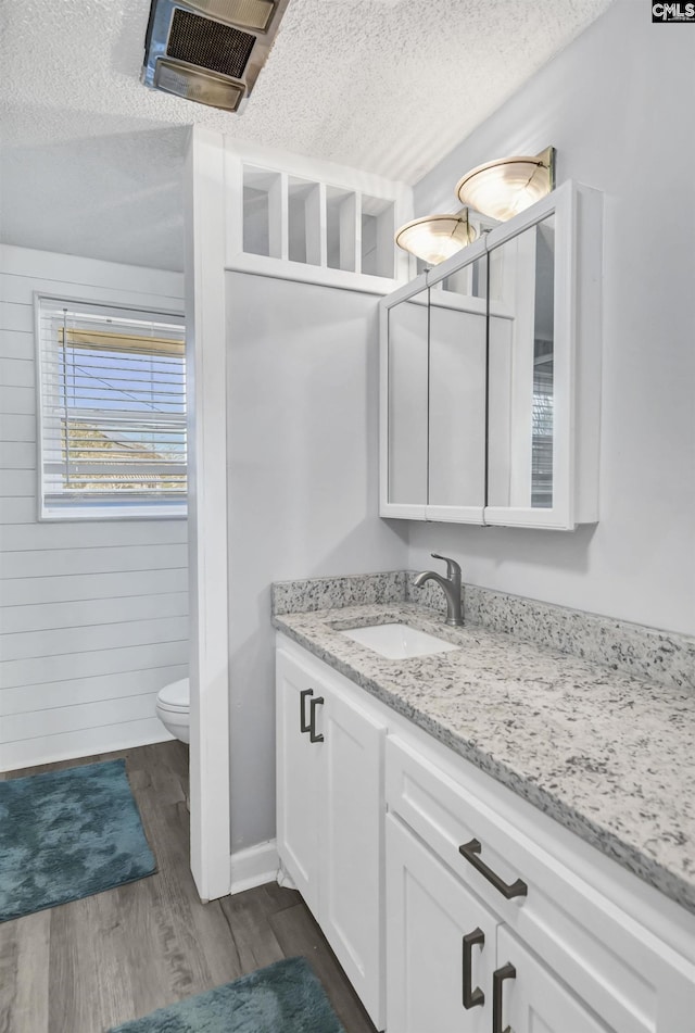 bathroom featuring visible vents, toilet, a textured ceiling, vanity, and wood finished floors