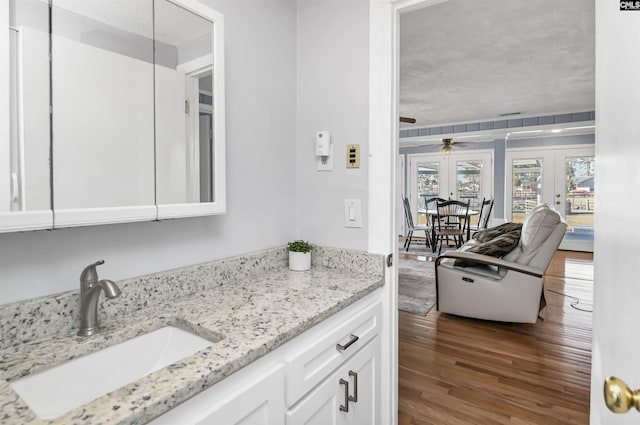 bathroom with ceiling fan, vanity, wood finished floors, and french doors