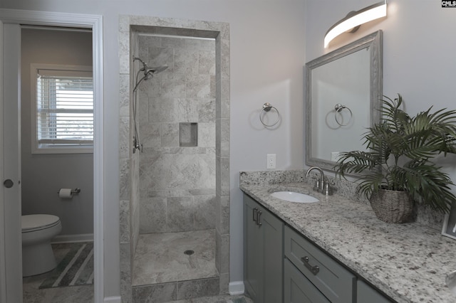 full bathroom with baseboards, a tile shower, vanity, and toilet