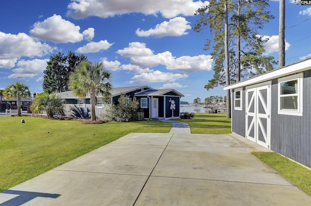 view of front facade featuring a front yard, a water view, and an outdoor structure