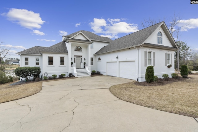 view of front of home with stucco siding, concrete driveway, an attached garage, and a shingled roof