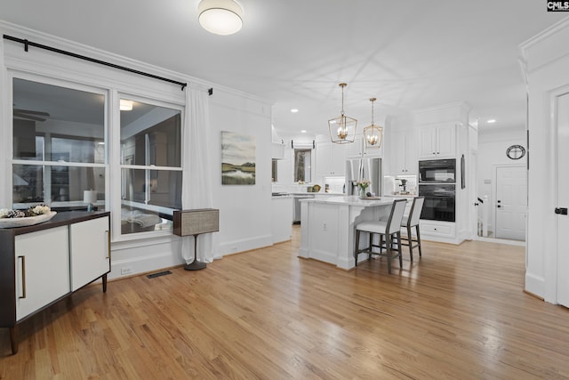 kitchen with visible vents, stainless steel fridge with ice dispenser, white cabinets, a kitchen bar, and light wood-type flooring