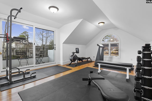 exercise area featuring baseboards, wood finished floors, and vaulted ceiling