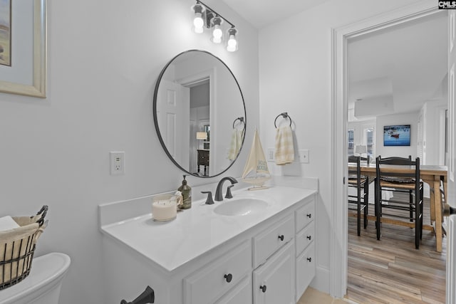 half bathroom featuring toilet, vanity, and wood finished floors