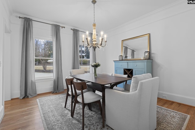 dining room featuring baseboards, an inviting chandelier, light wood-style flooring, and crown molding