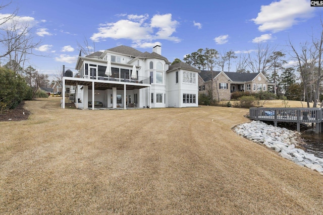 back of property with a yard, a deck, a chimney, and stucco siding