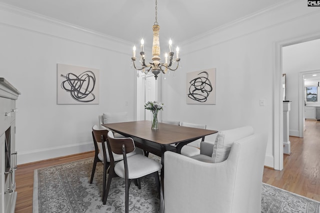 dining space featuring baseboards, an inviting chandelier, wood finished floors, and ornamental molding