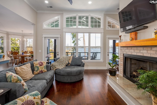 living room with ornamental molding, a wealth of natural light, a brick fireplace, and dark wood-style floors