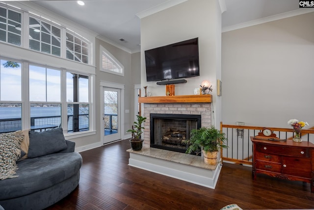 living room with a high ceiling, wood finished floors, baseboards, ornamental molding, and a brick fireplace