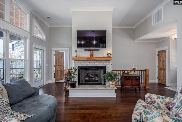 living room featuring a fireplace, visible vents, ornamental molding, a healthy amount of sunlight, and wood finished floors