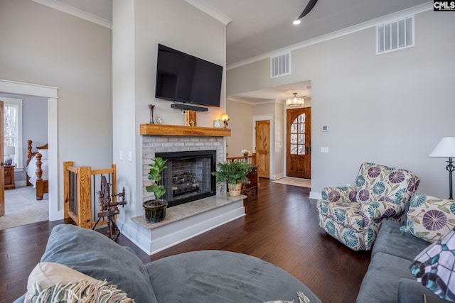 living room featuring visible vents, crown molding, a towering ceiling, and wood finished floors