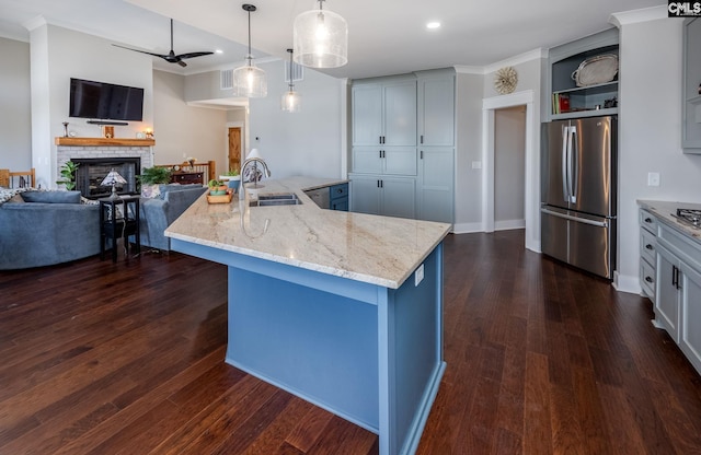 kitchen featuring dark wood-type flooring, a sink, open floor plan, a brick fireplace, and freestanding refrigerator