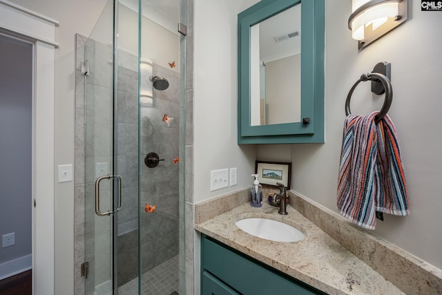 full bathroom featuring visible vents, a shower stall, and vanity