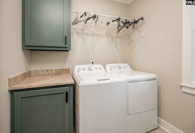 clothes washing area with washing machine and dryer, cabinet space, and baseboards