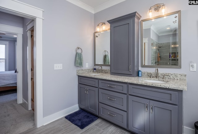 ensuite bathroom featuring double vanity, baseboards, ornamental molding, and a sink