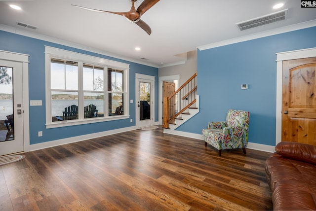 foyer entrance with ornamental molding, visible vents, stairway, and wood finished floors