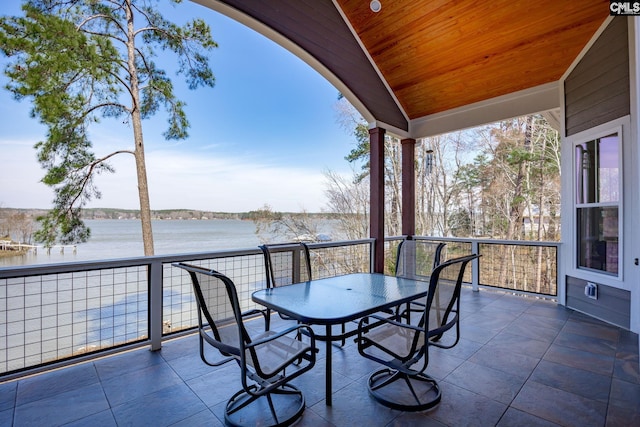 balcony with outdoor dining space and a water view