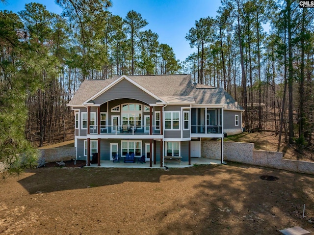 rear view of house with a sunroom, roof with shingles, a yard, and a patio