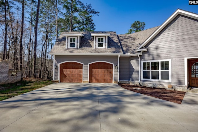 view of front of home featuring a garage, driveway, and a shingled roof