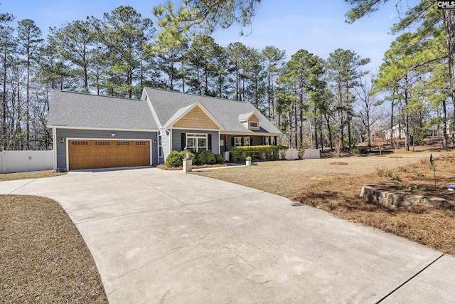 view of front of property with a garage, driveway, roof with shingles, and fence