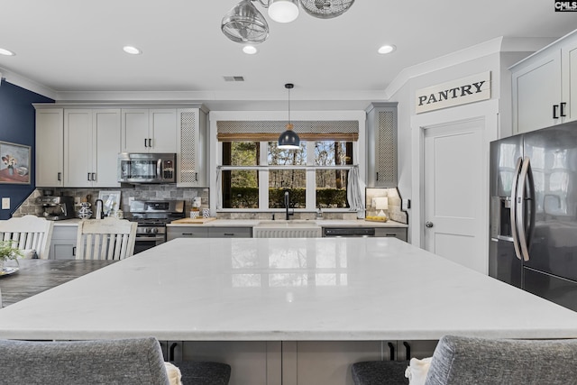 kitchen featuring stainless steel appliances, visible vents, a sink, and crown molding