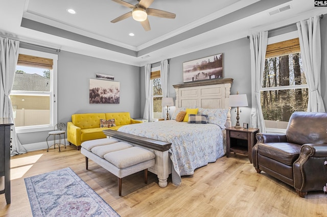 bedroom with visible vents, a tray ceiling, crown molding, light wood-style floors, and recessed lighting