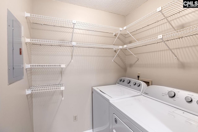 clothes washing area with laundry area, electric panel, a textured ceiling, and separate washer and dryer