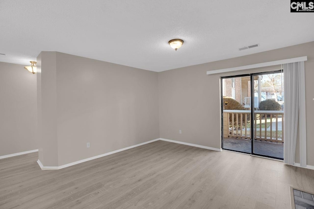 empty room with visible vents, baseboards, and wood finished floors