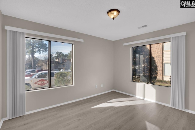 spare room featuring visible vents, baseboards, and wood finished floors