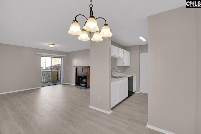 kitchen featuring light wood-style flooring, a sink, white cabinetry, light countertops, and dishwasher