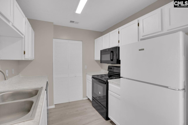 kitchen with light countertops, a sink, black appliances, and white cabinetry