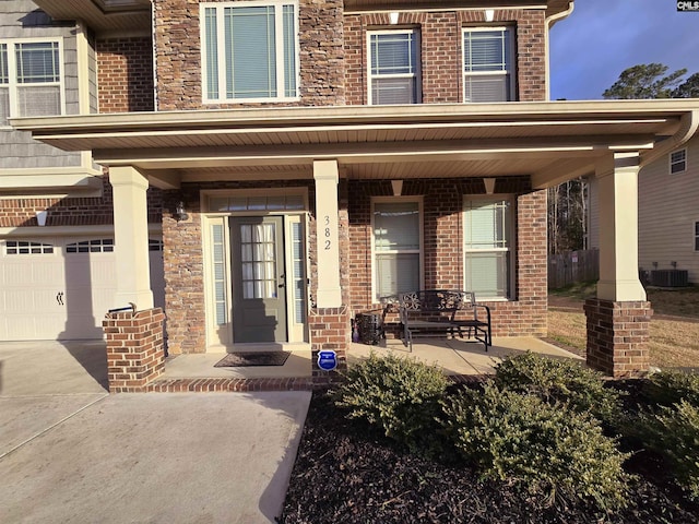 doorway to property with a garage, covered porch, and brick siding