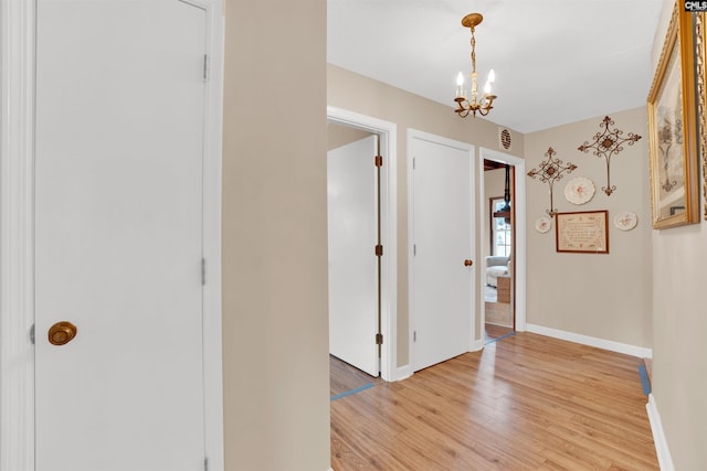 interior space featuring visible vents, light wood-type flooring, an inviting chandelier, and baseboards