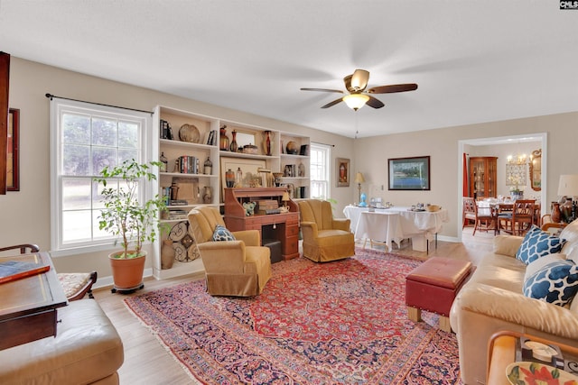 living area featuring ceiling fan, baseboards, and wood finished floors