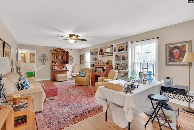 living room featuring ceiling fan, baseboards, and wood finished floors