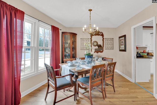 dining space featuring light wood-style floors, a notable chandelier, and baseboards